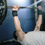 Man doing bench press with heavy barbell while wearing Bear KompleX Wrist Wraps